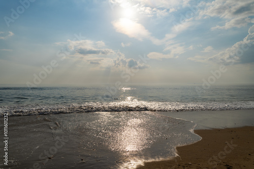 Coucher de soleil à la barre d'Étel, avec des reflets dorés sur l'eau, des nuages blancs dans le ciel et du sable doré. Une scène paisible de la rencontre entre la mer et le ciel.