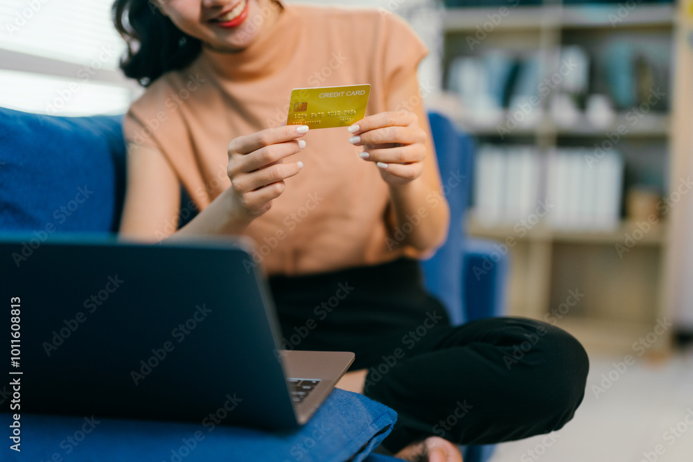 Woman happily shops online from her cozy home, using a credit card on her laptop, making secure transactions and enjoying the convenience Woman happily shops online from her cozy home, using a credit card on her laptop, making secure transactions and enjoying the convenience