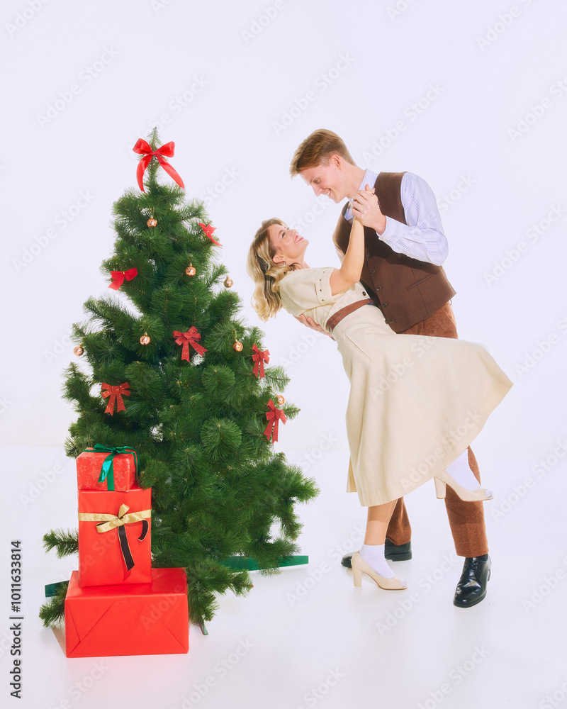 Couple shares romantic moment dancing beside Christmas tree, surrounded by holiday decorations and festive atmosphere. Concept of Merry Christmas, romance, fun and joy, celebration, holidays Couple shares romantic moment dancing beside Christmas tree, surrounded by holiday decorations and festive atmosphere. Concept of Merry Christmas, romance, fun and joy, celebration, holidays
