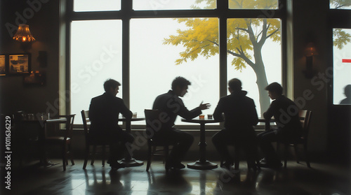 Silhouettes of people at a table in a cafe with an autumn landscape view