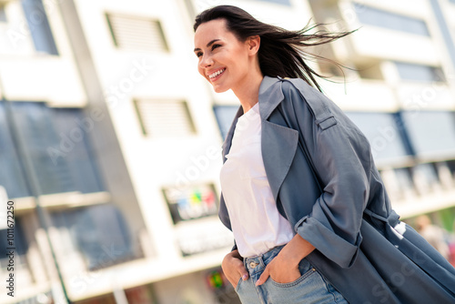 Photo of cheerful pretty lady dressed grey jacket smiling walking enjoying sunshine outdoors town street