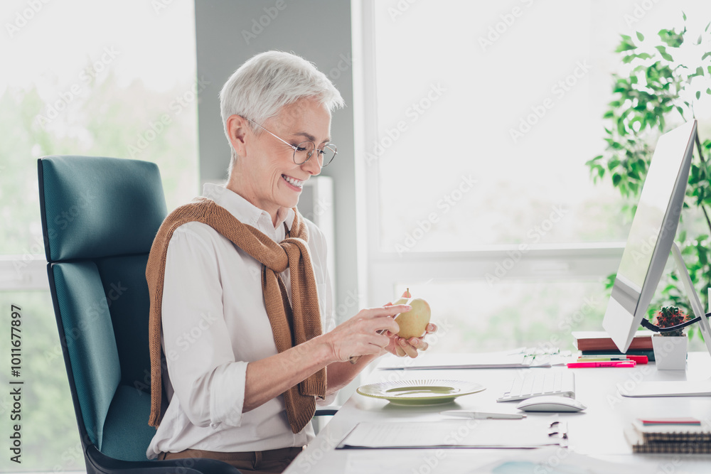 Photo of smart elderly chief female cut apple knife lunch wear formalwear comfortable modern office loft room interior indoors workspace Photo of smart elderly chief female cut apple knife lunch wear formalwear comfortable modern office loft room interior indoors workspace
