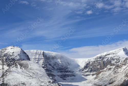 Wallpaper Mural Breathtaking snow-capped mountain peaks pierce azure sky. Massive glacier flows between rugged summits. Wispy clouds dance overhead. Pristine winter wonderland showcases nature's raw power.  Torontodigital.ca