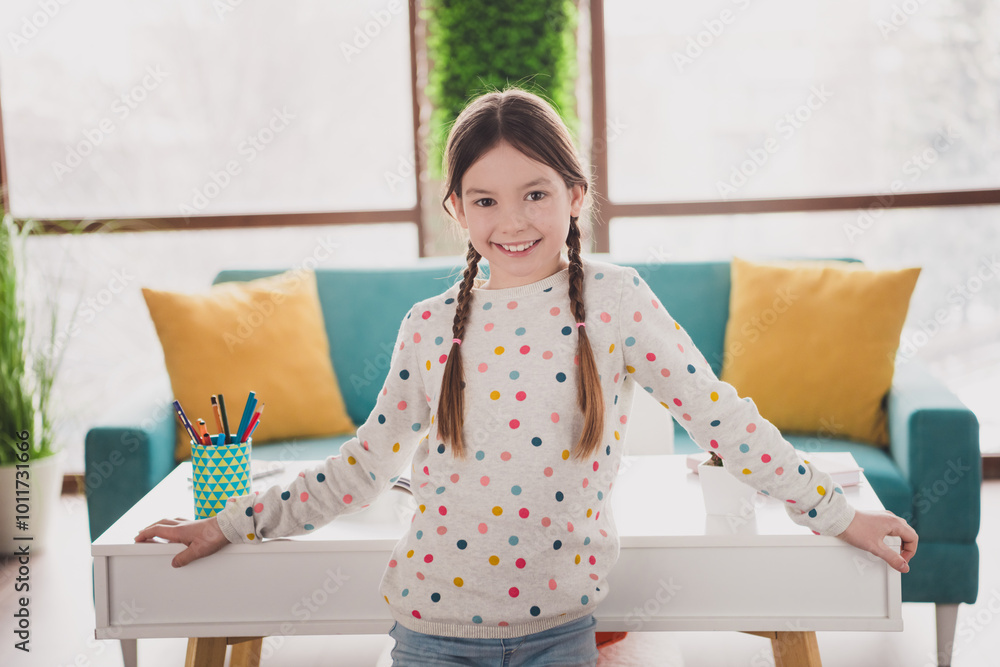 Photo of cute small schoolgirl toothy smile desk wear pullover modern interior apartment indoors Photo of cute small schoolgirl toothy smile desk wear pullover modern interior apartment indoors