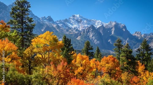 A majestic mountain view with trees showcasing autumn colors in the foreground, clear blue sky above