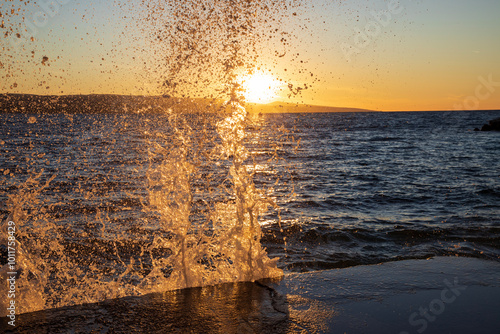 Fototapeta Naklejka Na Ścianę i Meble -  Sea waves splashing against the promenade in Brela, Croatia at sunset