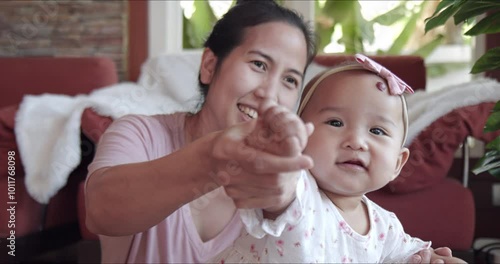 Cute Asian baby girl smiling while playing with mom. Candid portrait of healthy infant having fun and look at camera. Small family, single parent with one child, concept.