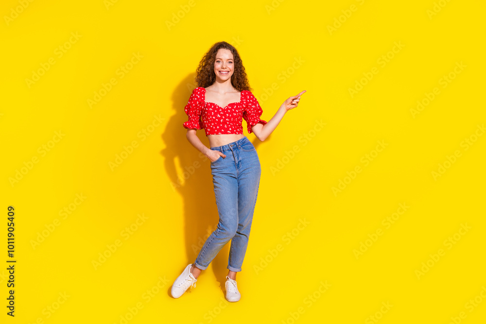 Full length photo of lovely young lady posing model point empty space dressed stylish red garment isolated on yellow color background Full length photo of lovely young lady posing model point empty space dressed stylish red garment isolated on yellow color background
