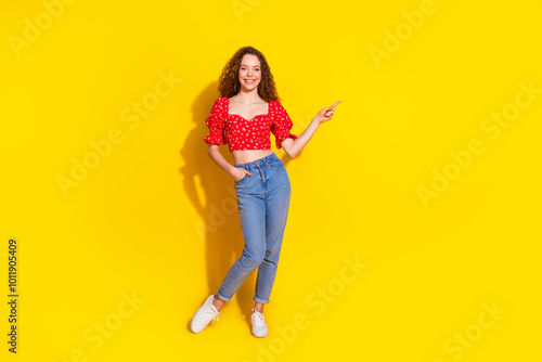 Full length photo of lovely young lady posing model point empty space dressed stylish red garment isolated on yellow color background