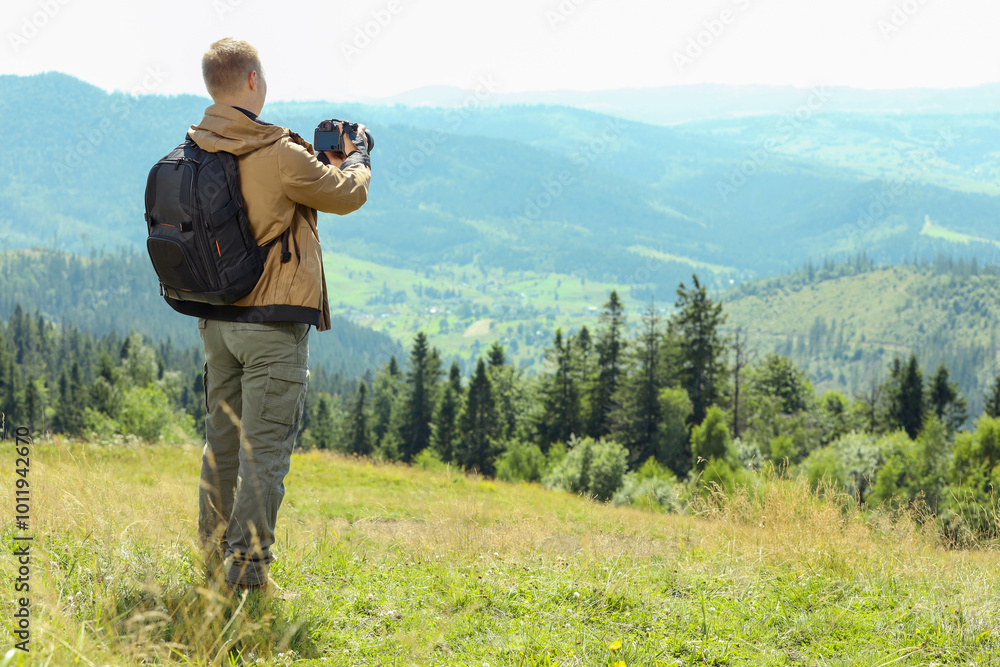 Photographer with backpack and camera taking picture of beautiful mountains, back view. Space for text Photographer with backpack and camera taking picture of beautiful mountains, back view. Space for text