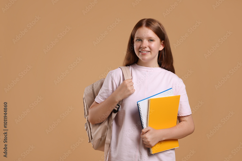 Teenage girl with backpack and books on beige background, space for text Teenage girl with backpack and books on beige background, space for text