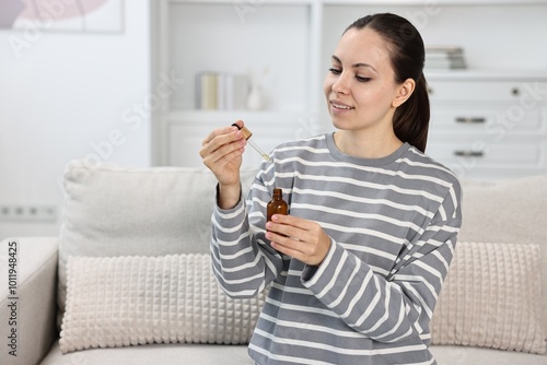 Young woman taking CBD tincture indoors, space for text photo