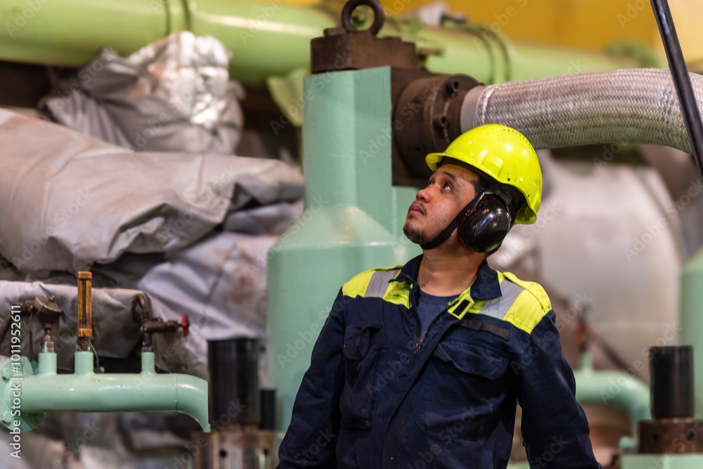 A close-up of the upper body and head of a marine engineer officer, focused on performing duties in the engine room during the repair of the ship’s main engine.
