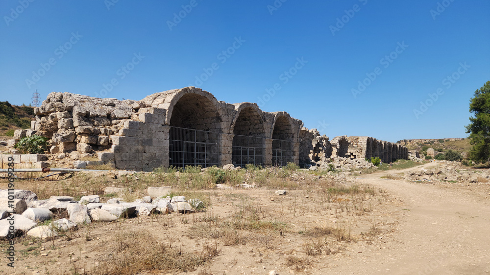 Fototapeta premium Arched stone buildiings in the eastern side of the stadium of the Perge ancient city located in Aksu district of Antalya province in Turkey