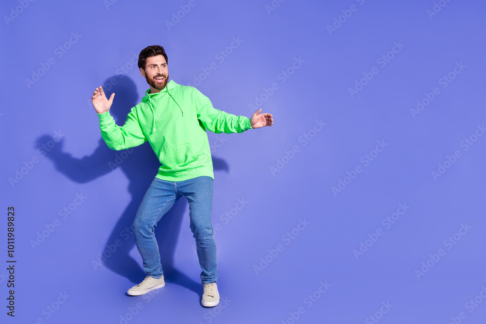 Full body photo of attractive young man surfing keep balance empty space dressed stylish green clothes isolated on violet color background Full body photo of attractive young man surfing keep balance empty space dressed stylish green clothes isolated on violet color background