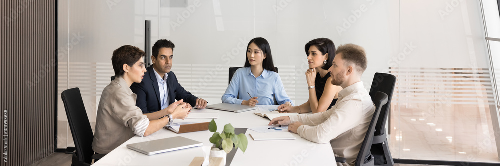 Group of multiethnic coworkers talking at large meeting table in modern office space, talking, discussing business communication, project, teamwork, sharing ideas for brainstorming. Banner shot Group of multiethnic coworkers talking at large meeting table in modern office space, talking, discussing business communication, project, teamwork, sharing ideas for brainstorming. Banner shot