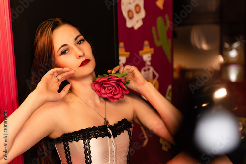 Beautiful girl in a corset posing while sitting. Holds a flower in his hand, looks intimidatingly into the camera. Halloween concept, nightclub, masquerade photo