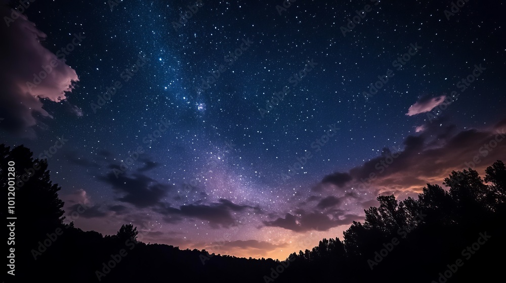 Fototapeta premium The dark night sky, filled with twinkling stars and a few fluffy clouds.