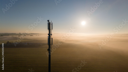 5G Tower in Misty Sunrise Over Expansive Rural Landscape photo