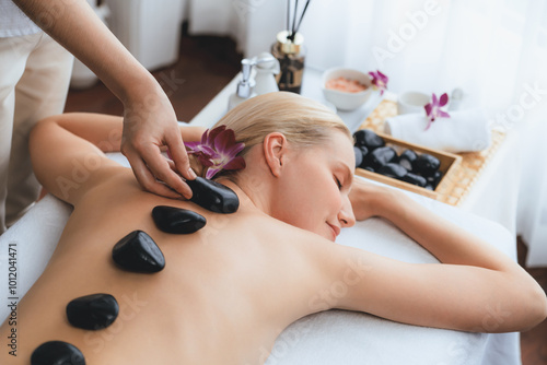 фотографія Hot stone massage at spa salon in luxury resort with day light serenity ambient, blissful woman customer enjoying spa basalt stone massage glide over body with soothing warmth