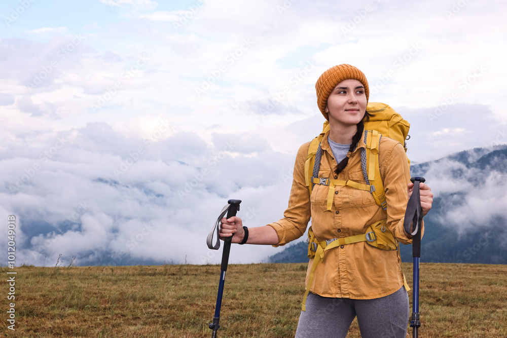 Young hiker with trekking poles and backpack in mountains outdoors, space for text Young hiker with trekking poles and backpack in mountains outdoors, space for text