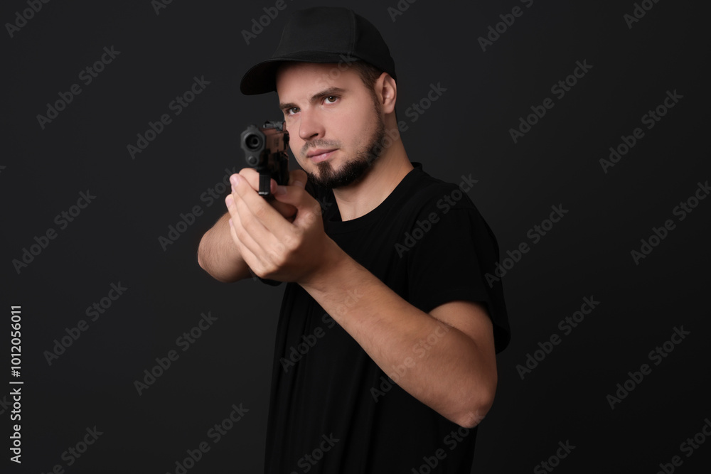 Young bodyguard using gun on black background Young bodyguard using gun on black background