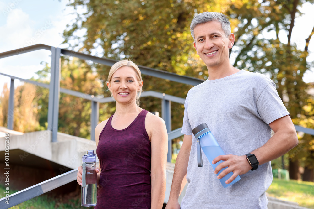 Happy couple with bottles of water in park Happy couple with bottles of water in park