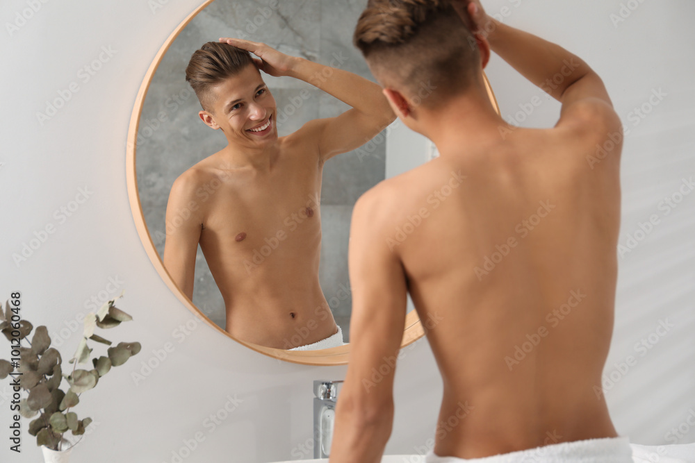 Obraz premium Handsome man looking at mirror in bathroom