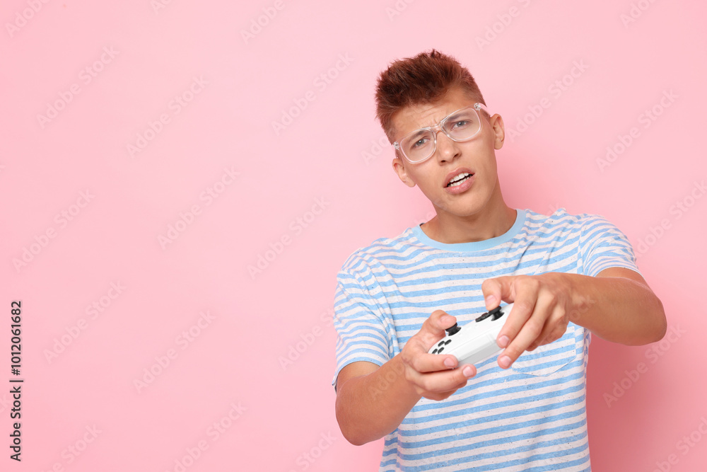 Young man playing video games with controller on pink background, space for text Young man playing video games with controller on pink background, space for text