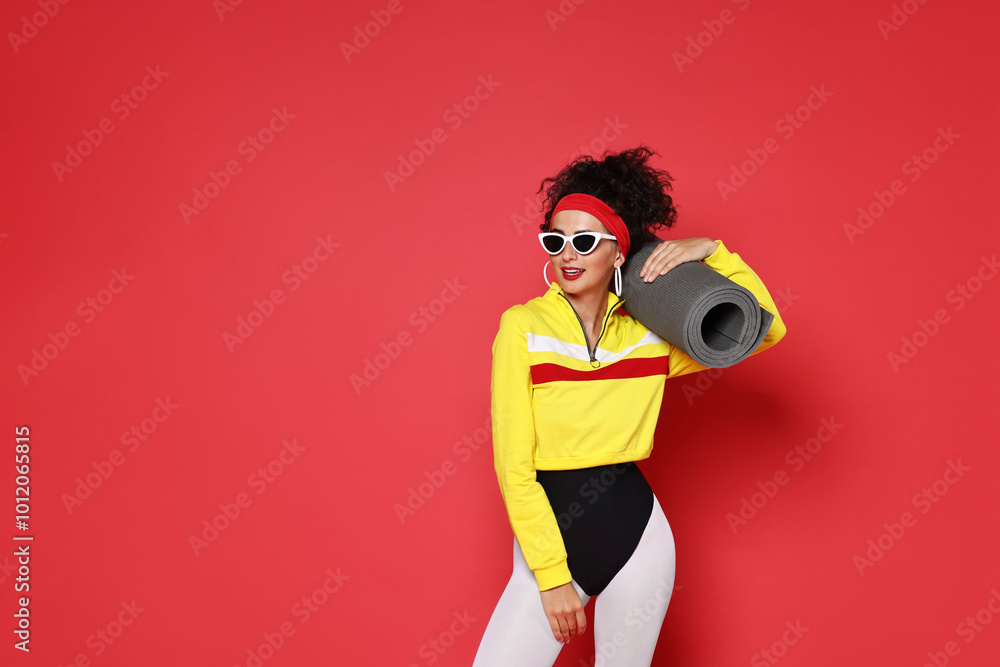 Obraz premium Aerobics. Woman in sportswear holding fitness mat on red background, space for text