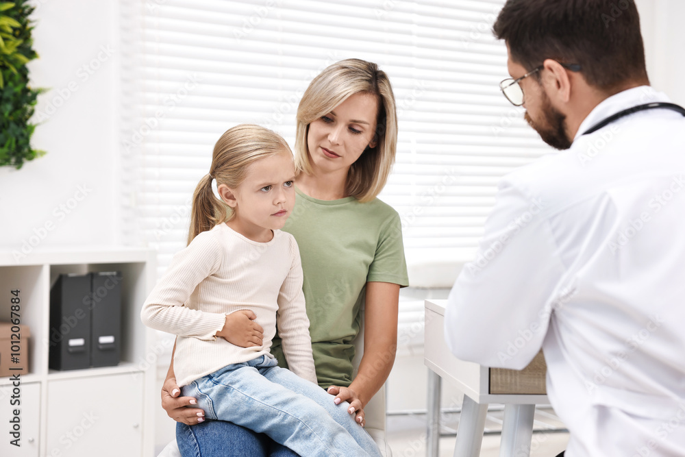 Obraz premium Doctor consulting little girl with stomach pain and her mother in hospital, back view