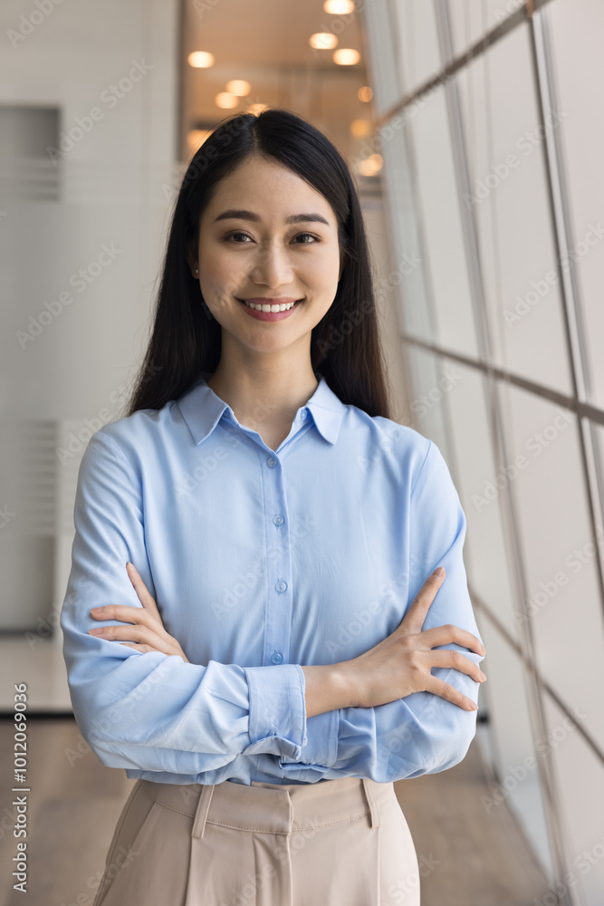 Happy beautiful Asian business woman vertical portrait. Cheerful positive young professional girl, manager, employee posing for head shot with arms crossed, looking at camera, smiling Happy beautiful Asian business woman vertical portrait. Cheerful positive young professional girl, manager, employee posing for head shot with arms crossed, looking at camera, smiling