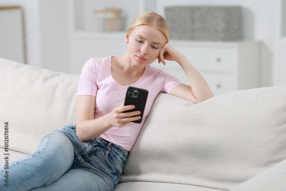 Beautiful woman using smartphone on sofa indoors Beautiful woman using smartphone on sofa indoors