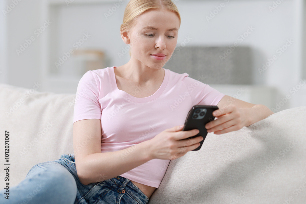 Beautiful woman using smartphone on sofa indoors Beautiful woman using smartphone on sofa indoors