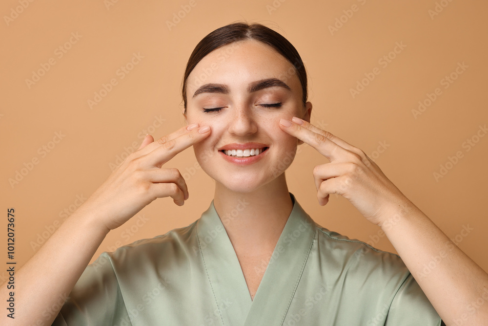 Face massage. Beautiful young woman with healthy skin on beige background Face massage. Beautiful young woman with healthy skin on beige background