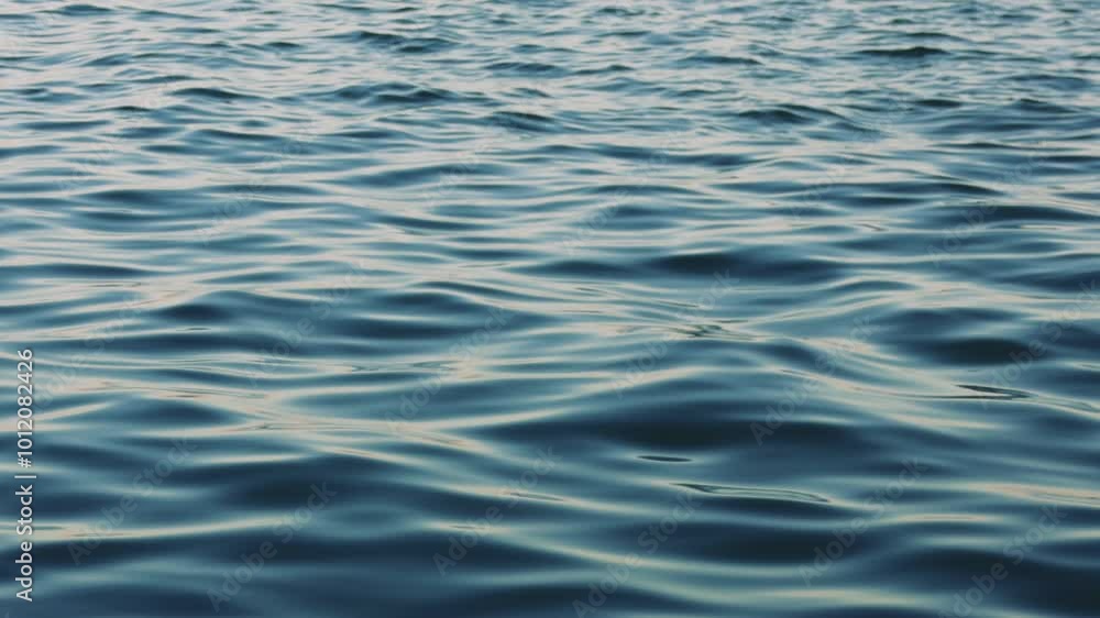 Gentle waves ripple across a deep blue water surface, highlighting nature's beauty and power. The dynamic movement creates a tranquil and serene atmosphere Gentle waves ripple across a deep blue water surface, highlighting nature's beauty and power. The dynamic movement creates a tranquil and serene atmosphere