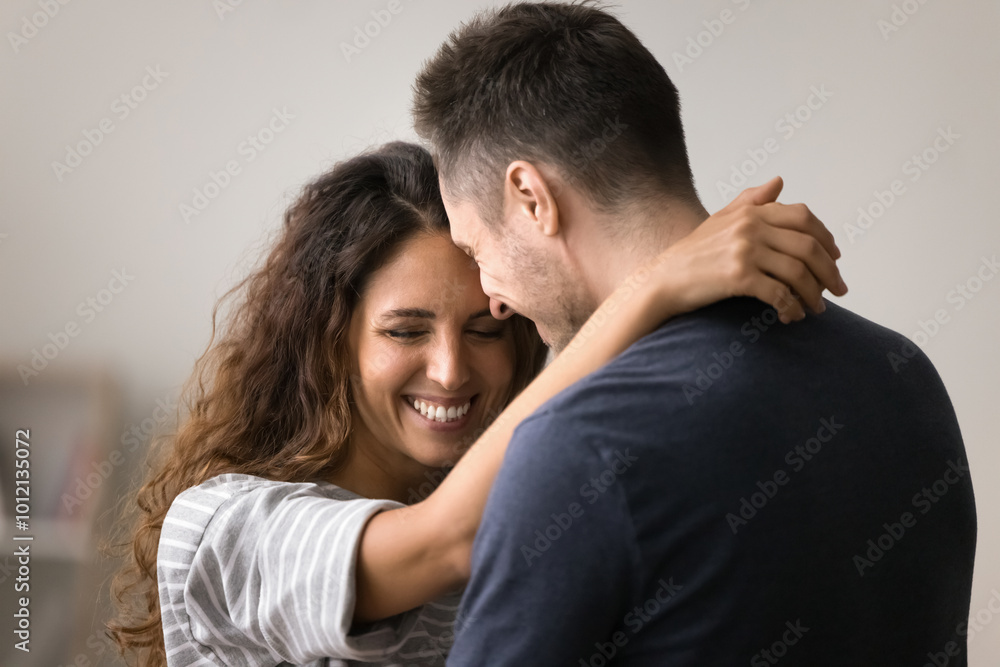 Happy pretty wife embracing husbands neck with love, affection, tenderness, smiling. Positive cheerful couple dancing at home, hugging, enjoying romantic leisure, talking, laughing Happy pretty wife embracing husbands neck with love, affection, tenderness, smiling. Positive cheerful couple dancing at home, hugging, enjoying romantic leisure, talking, laughing