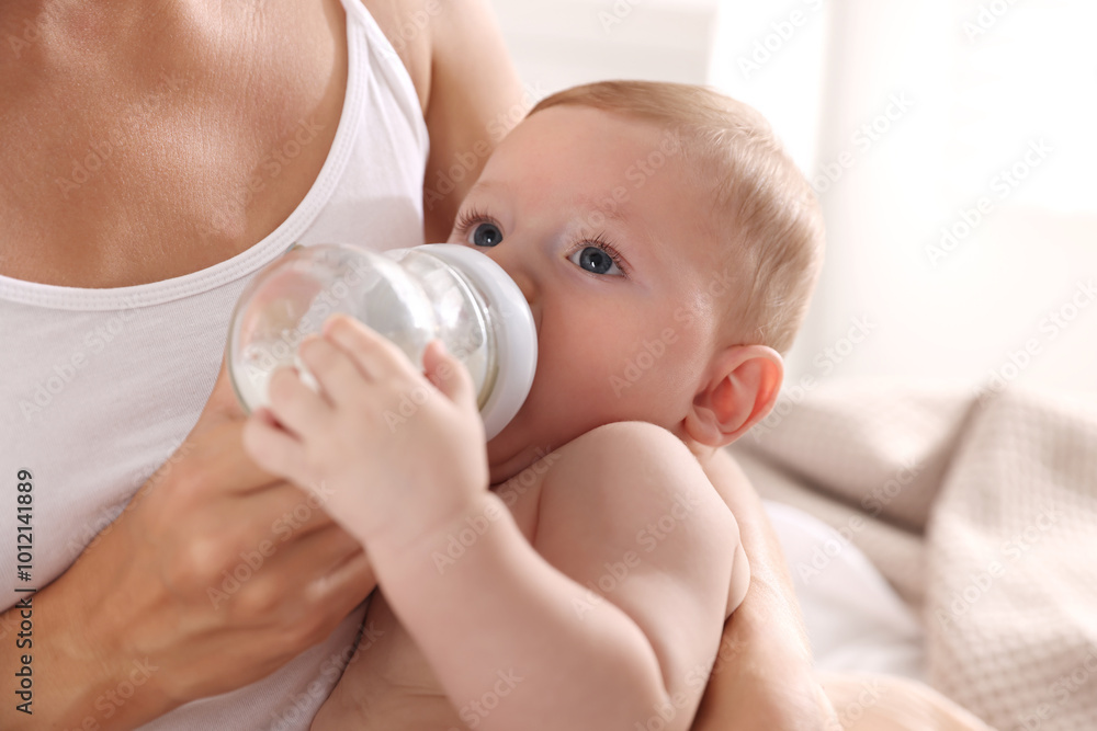 Mother feeding her cute child indoors, closeup Mother feeding her cute child indoors, closeup