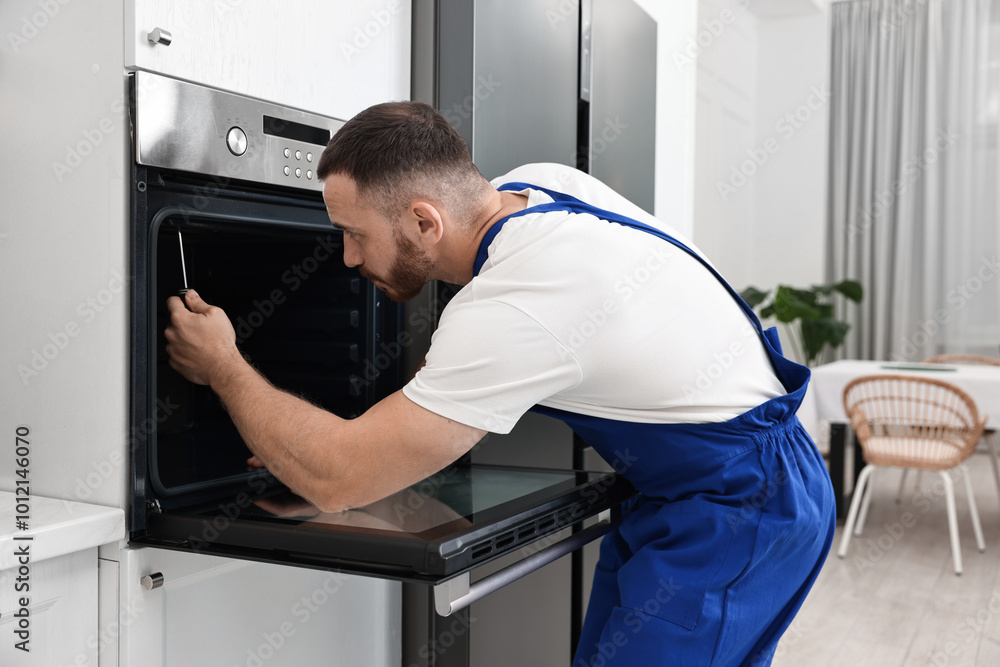 Repairman with screwdriver fixing oven at home Repairman with screwdriver fixing oven at home