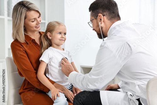 Doctor examining little girl with stethoscope and her mother in hospital