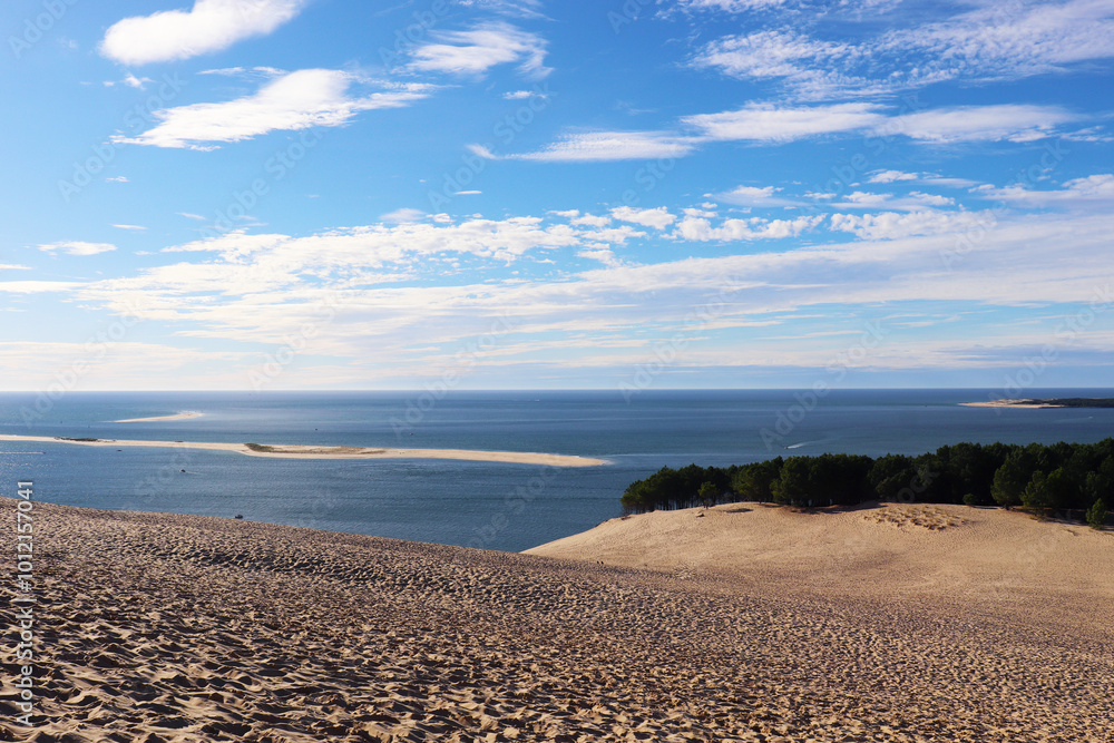 large sand dune with ocean and blue sky in the background large sand dune with ocean and blue sky in the background