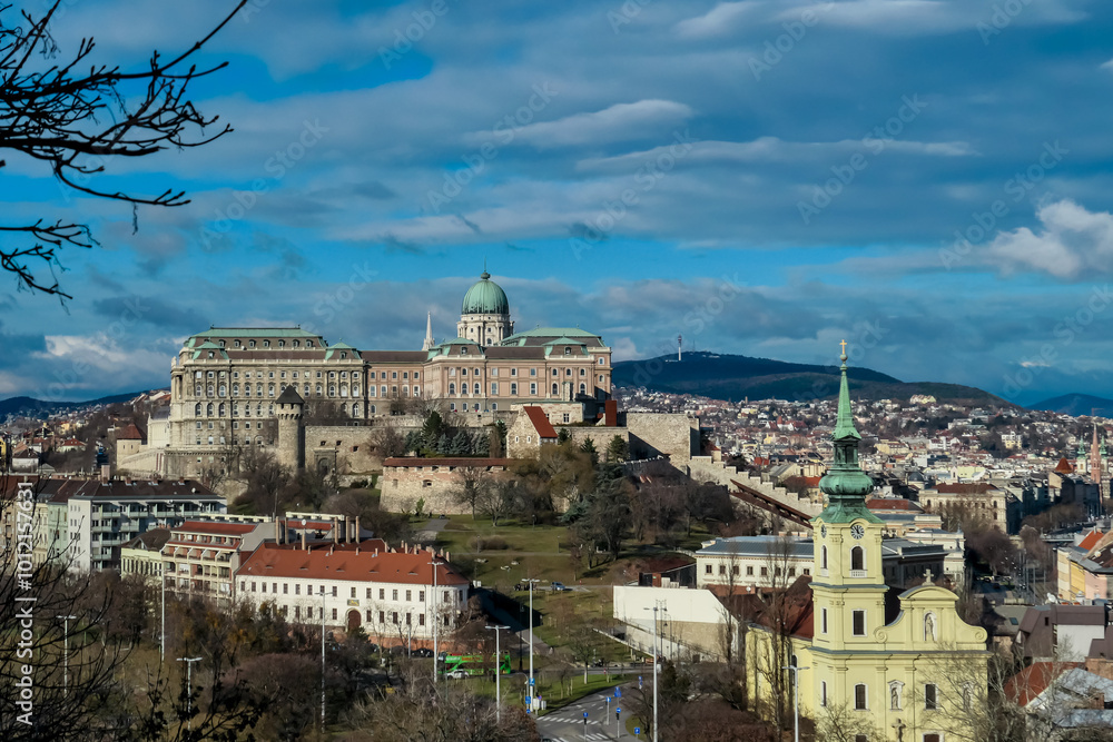 Fototapeta premium Panoramic view of iconic Buda castle in Budapest, Hungary. Sprawling complex of buildings, dominates the center of the scene. The landmark sits atop a hill overlooking the city and the Danube River.