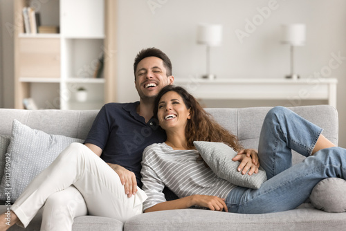 Bilde på lerret Joyful married couple in love resting on comfortable sofa, hugging with affectio