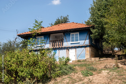 Old blue painted rural house on hillside of Balkan village closeup on sunny summer day