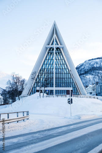 Arctic Cathedral in Tromso, Norway in winter. Tromsdalen Church with unusual modernist architecture and glass facade in snowy landscape. Vertical orientation