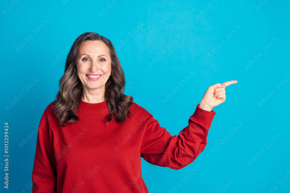 Portrait of nice aged woman point finger empty space wear red sweater isolated on blue color background Portrait of nice aged woman point finger empty space wear red sweater isolated on blue color background