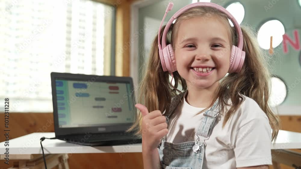 Smiling girl using laptop and turn around to show thumb up to camera ...