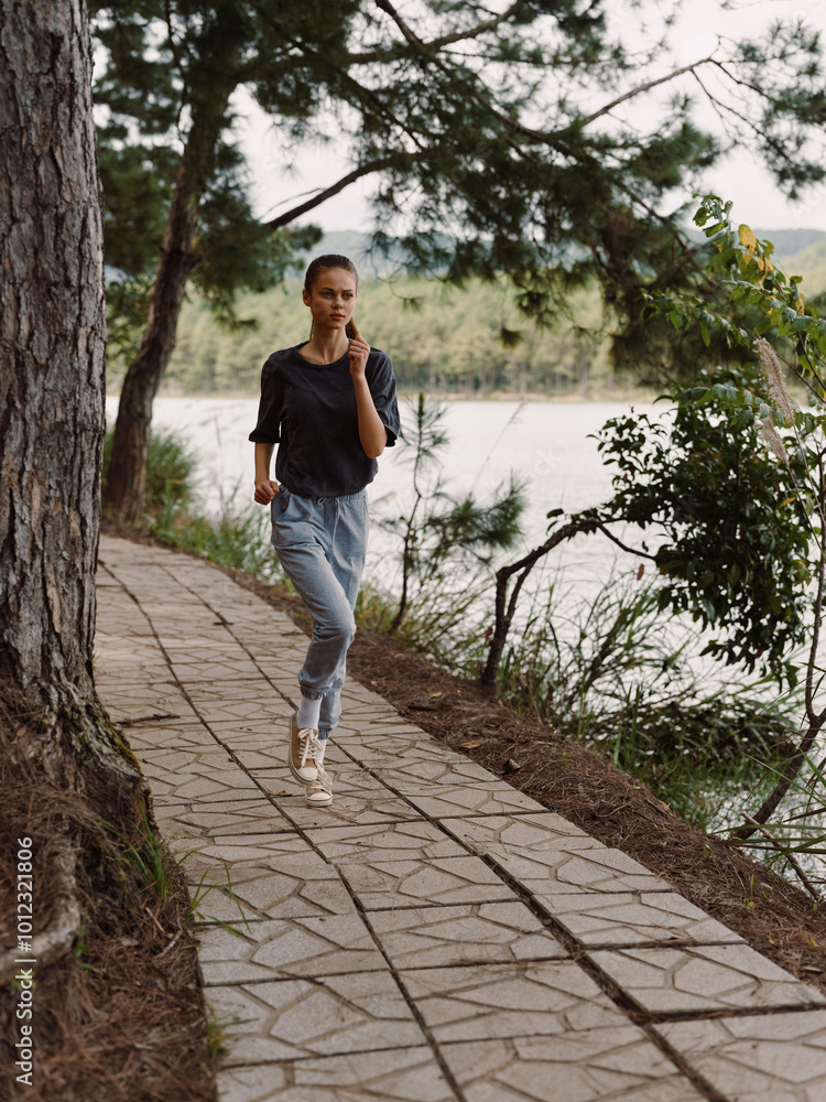 Young woman jogging along a scenic path by the lake, wearing comfortable athletic clothing, enjoying nature and fresh air Fitness and health concept Young woman jogging along a scenic path by the lake, wearing comfortable athletic clothing, enjoying nature and fresh air Fitness and health concept