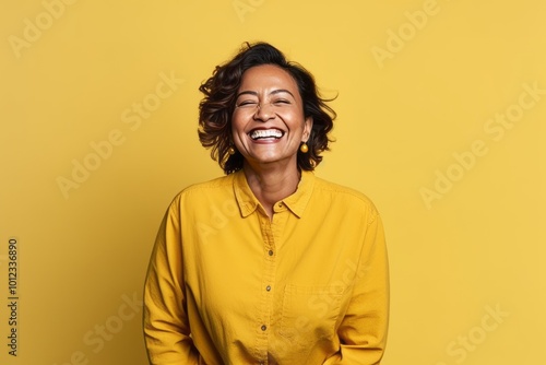 Portrait of happy african american woman laughing over yellow background