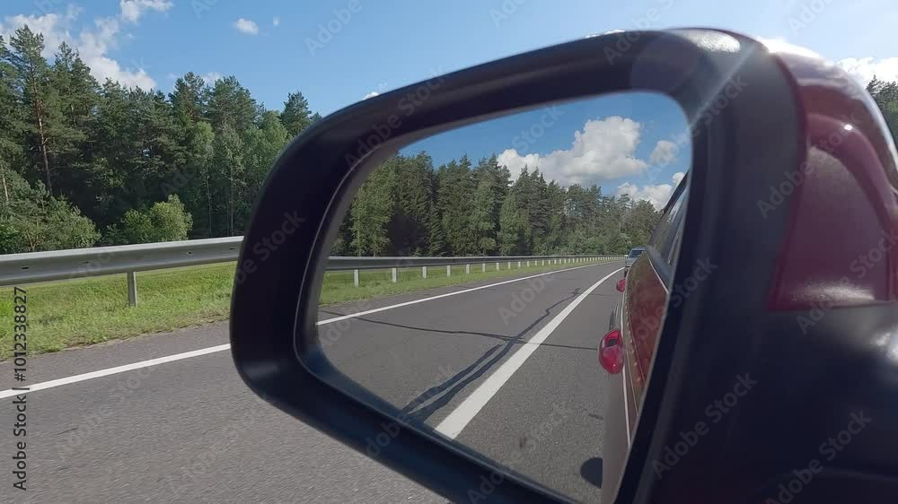 Video shooting in motion, view in the rear view side mirror of a auto, driving a red car along the road Video shooting in motion, view in the rear view side mirror of a auto, driving a red car along the road